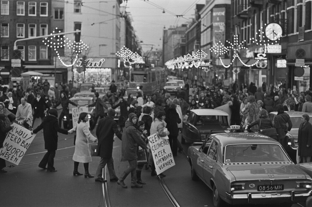 Foto em preto e branco de pessoas bloqueando uma rua de Amsterdã com cartazes